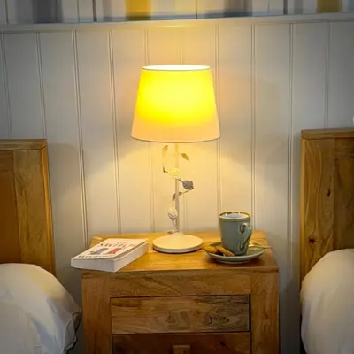 a lamp on a table with a book and a cup at Sibton White Horse Inn in Saxmundham