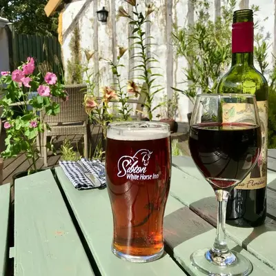a glass of beer and a bottle of wine on a table at Sibton White Horse Inn in Saxmundham