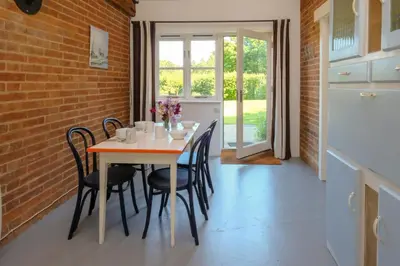 a dining room with a table and chairs and a brick wall at The Dairy Cottage in Aldeburgh