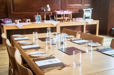 a long wooden table with plates and glasses on it at West Court- Jesus College in Cambridge