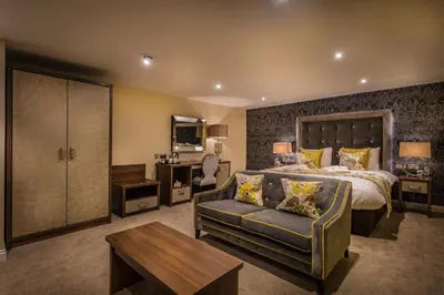 a large bedroom with a bed and a couch at The Golden Lion Hotel, St Ives, Cambridgeshire - The Coaching Inn Group in St Ives