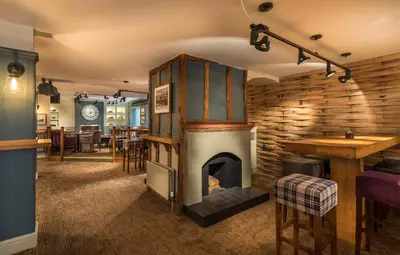 a living room with a wood stove in a room at The Golden Lion Hotel, St Ives, Cambridgeshire - The Coaching Inn Group in St Ives