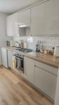 a kitchen with white cabinets and a wooden counter top at Welcome Home in Royston