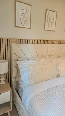a bed in a bedroom with two pictures on the wall at Welcome Home in Royston