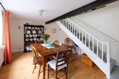 a dining room with a table and a staircase at Pear Tree Cottage in Aldeburgh