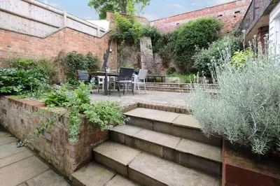 a patio with a table and chairs in a garden at Pear Tree Cottage in Aldeburgh