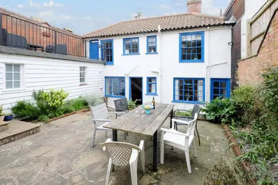 a patio with a wooden table and chairs at Pear Tree Cottage in Aldeburgh