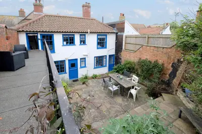 a house with a table and chairs in a yard at Pear Tree Cottage in Aldeburgh