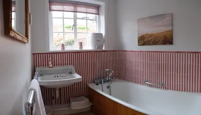 a bathroom with a bath tub and a sink at Pear Tree Cottage in Aldeburgh