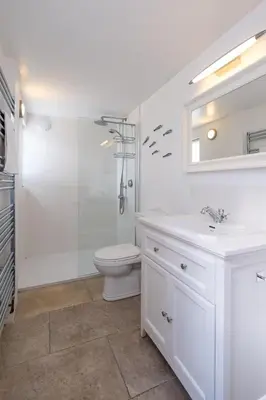a white bathroom with a shower and a toilet at Pear Tree Cottage in Aldeburgh
