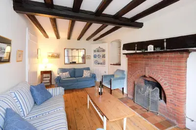 a living room with a brick fireplace and blue couches at Pear Tree Cottage in Aldeburgh