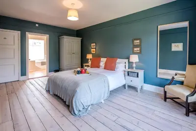 a bedroom with a large bed and a chair at Hillcrest, Aldeburgh in Aldeburgh