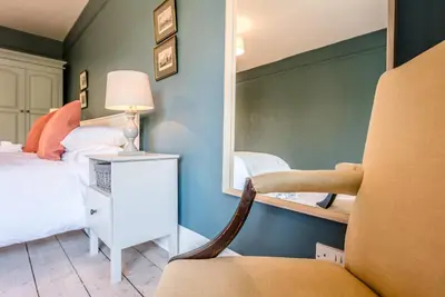 a bedroom with a bed and a mirror and a chair at Hillcrest, Aldeburgh in Aldeburgh