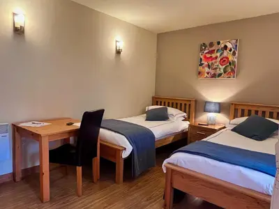 a room with two beds and a desk and a table at Orchard Cottage in Willingham