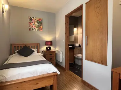 a bedroom with a bed and a bathroom at Orchard Cottage in Willingham