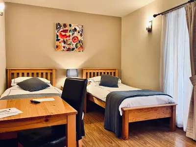 a room with two beds and a desk and a table at Orchard Cottage in Willingham