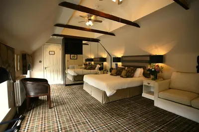a bedroom with two beds and a chair and a couch at The White Hart in Great Yeldham