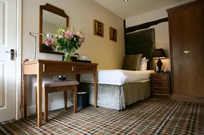 a bedroom with a bed and a table with a vase of flowers at The White Hart in Great Yeldham