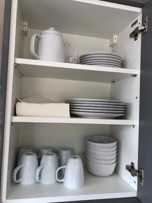 a cupboard filled with white dishes and plates at Guineas House in Newmarket