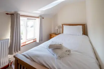 a bedroom with a white bed with towels on it at 3 Beach Cottages - Aldeburgh Coastal Cottages in Thorpeness