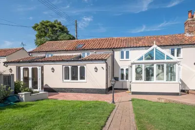 a white house with a conservatory in a yard at 3 Beach Cottages - Aldeburgh Coastal Cottages in Thorpeness