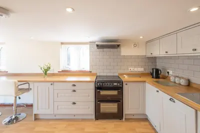 a kitchen with white cabinets and a black stove at 3 Beach Cottages - Aldeburgh Coastal Cottages in Thorpeness