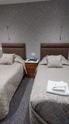 two beds sitting next to each other in a bedroom at Grove House Hotel in Woodbridge