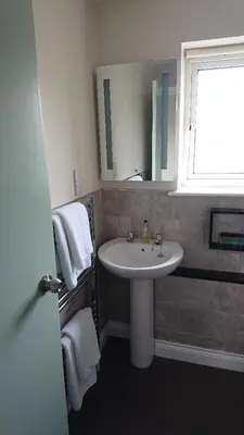a bathroom with a white sink and a window at Grove House Hotel in Woodbridge