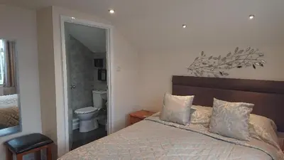 a bedroom with a bed and a bathroom with a toilet at Grove House Hotel in Woodbridge