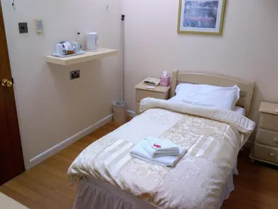 a small bedroom with a bed with towels on it at Grove House Hotel in Woodbridge