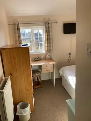 a bedroom with a desk and a bed and a window at Grove House Hotel in Woodbridge