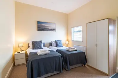 a bedroom with two beds and a mirror at Greyfriars in Clacton-on-Sea