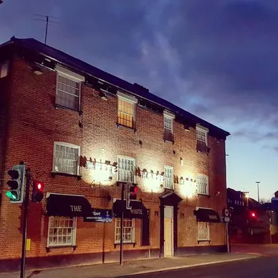 a large brick building on the corner of a street at The White Horse Hotel in Leiston