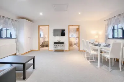 a living room with a table and white chairs at Highgate Annexe in Takeley
