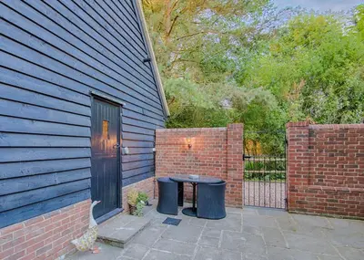 a patio with a table next to a brick wall at Highgate Annexe in Takeley