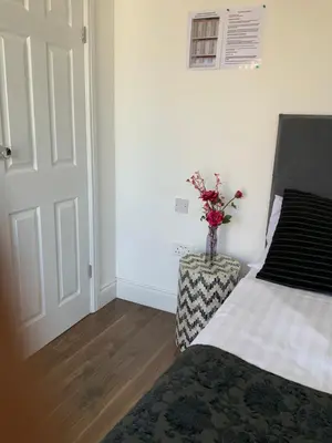 a bedroom with a bed and a vase of flowers on a table at Stanwell Stansted Airport in Takeley