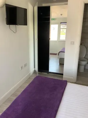 a living room with a purple rug and a tv at Stanwell Stansted Airport in Takeley