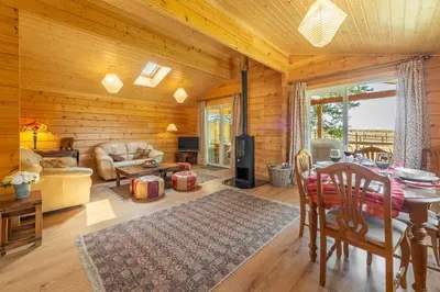a living room with wooden walls and a table in a cabin at The Lodge in Stowmarket