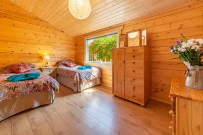 a log cabin bedroom with two beds and a window at The Lodge in Stowmarket