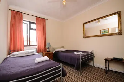 a hotel room with two beds and a mirror at The Rathmore in Cambridge