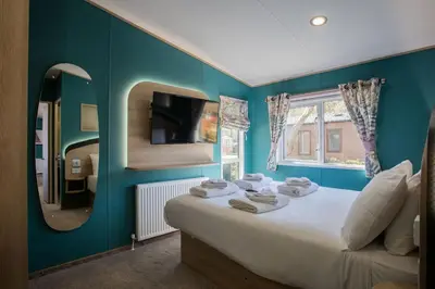 a bedroom with a large bed and a mirror at Mersea Island by Away Resorts in Colchester