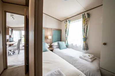 two beds in a small room with a window at Mersea Island by Away Resorts in Colchester