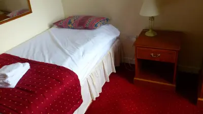 a bedroom with a bed and a dresser with a red blanket at The Griffin Hotel in Attleborough