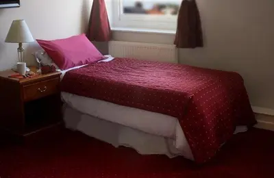 a bedroom with a bed with a pink blanket and a table at The Griffin Hotel in Attleborough