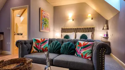 a living room with a couch with colorful pillows at The Pheasant Public House & Hotel in Gestingthorpe
