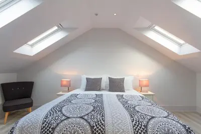 a bedroom with a bed with two lamps and a chair at Citystay Living - Midsummer Mews in Cambridge