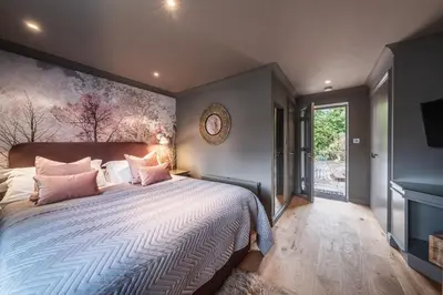 a bedroom with a large bed with pink pillows at The Cricketers Clavering in Clavering
