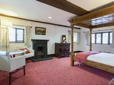 a bedroom with a canopy bed and a fireplace at Hockwold Hall in Hockwold cum Wilton