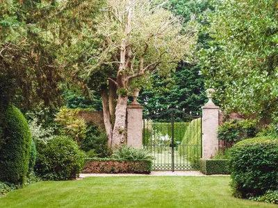 a gate in a garden with green grass and trees at Hockwold Hall in Hockwold cum Wilton