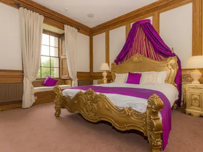 a bedroom with a king sized bed with a purple canopy at Hockwold Hall in Hockwold cum Wilton